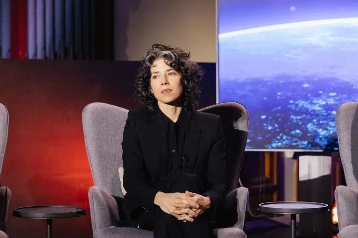 A woman seated on a conference stage during a discussion.