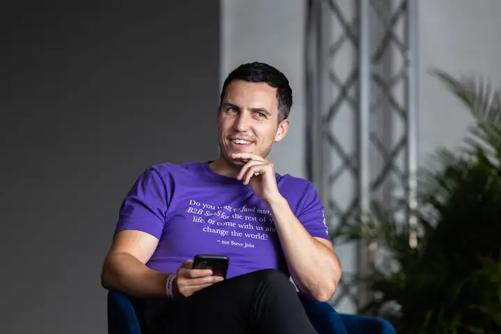 A seated speaker holding a phone during an interview.