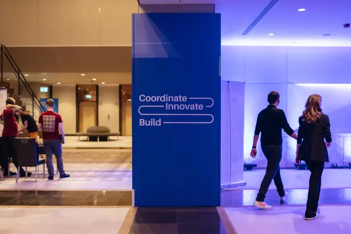 Attendees walking through a blue-lit conference foyer.