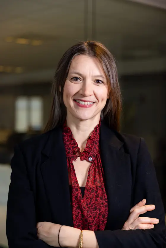 Portrait of a smiling woman with folded arms in an office.